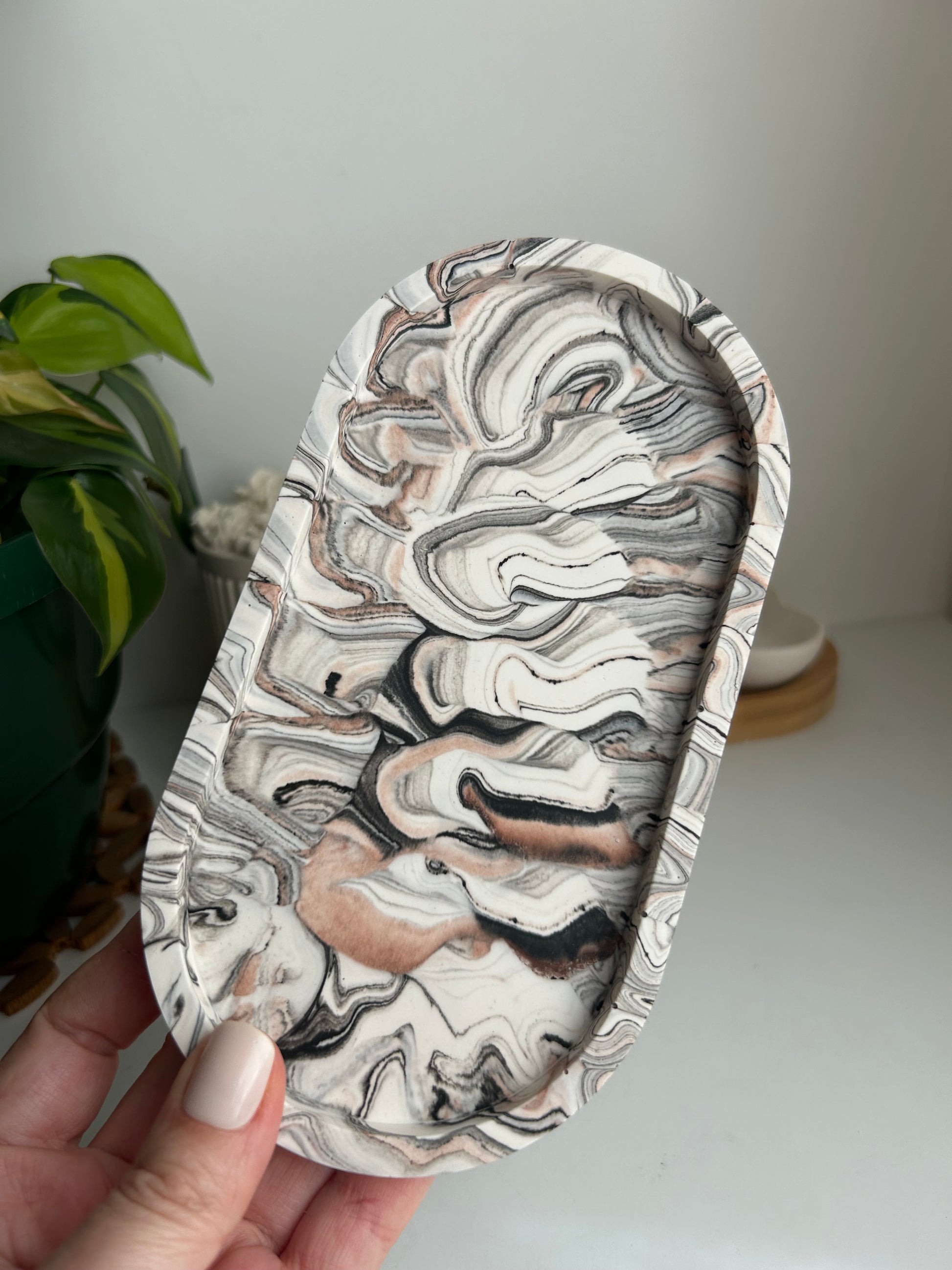 Black and Beige tray held by a hand with a plant in the background