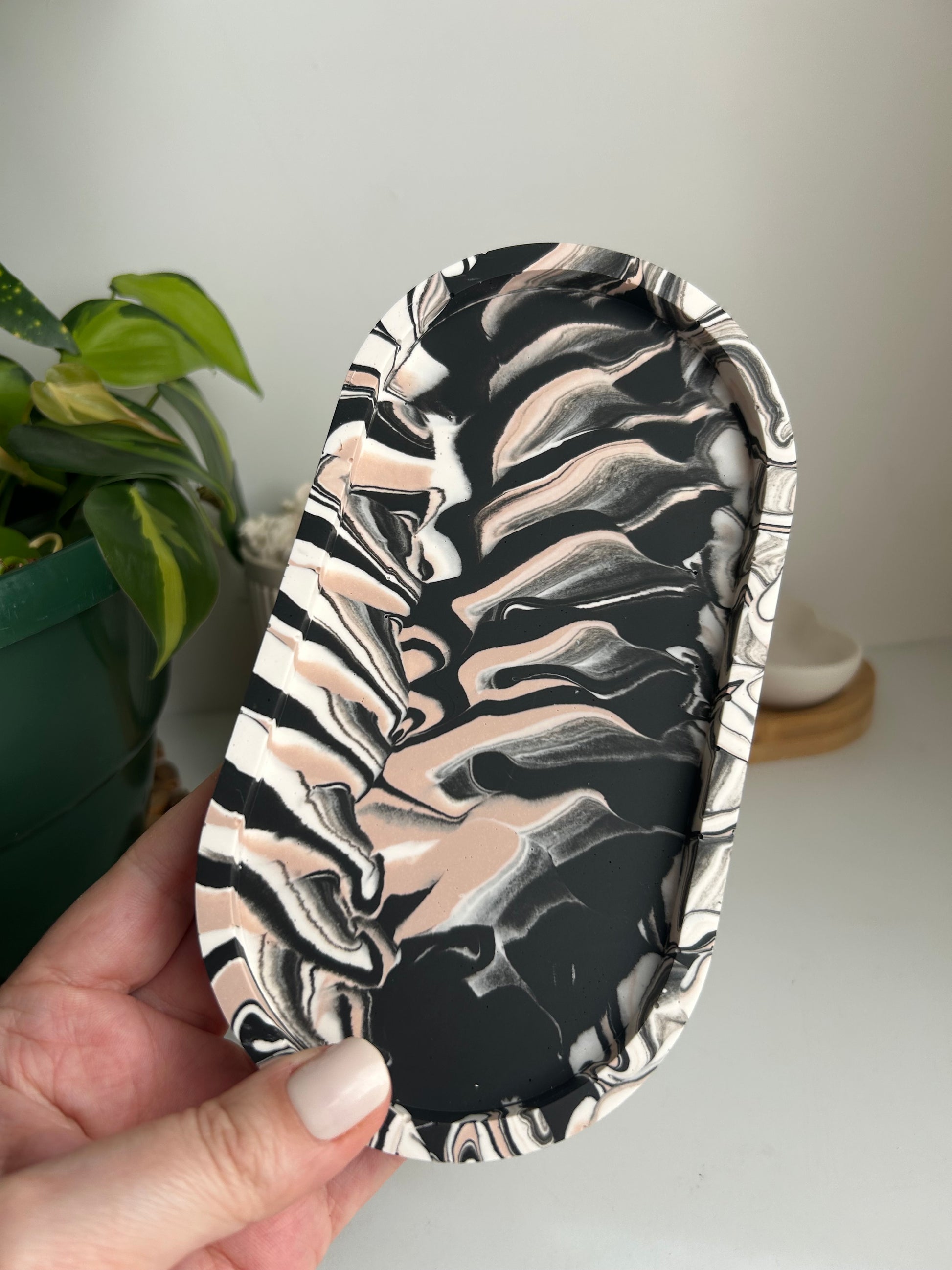 Marbled black and white tray held by a hand with a plant in the background