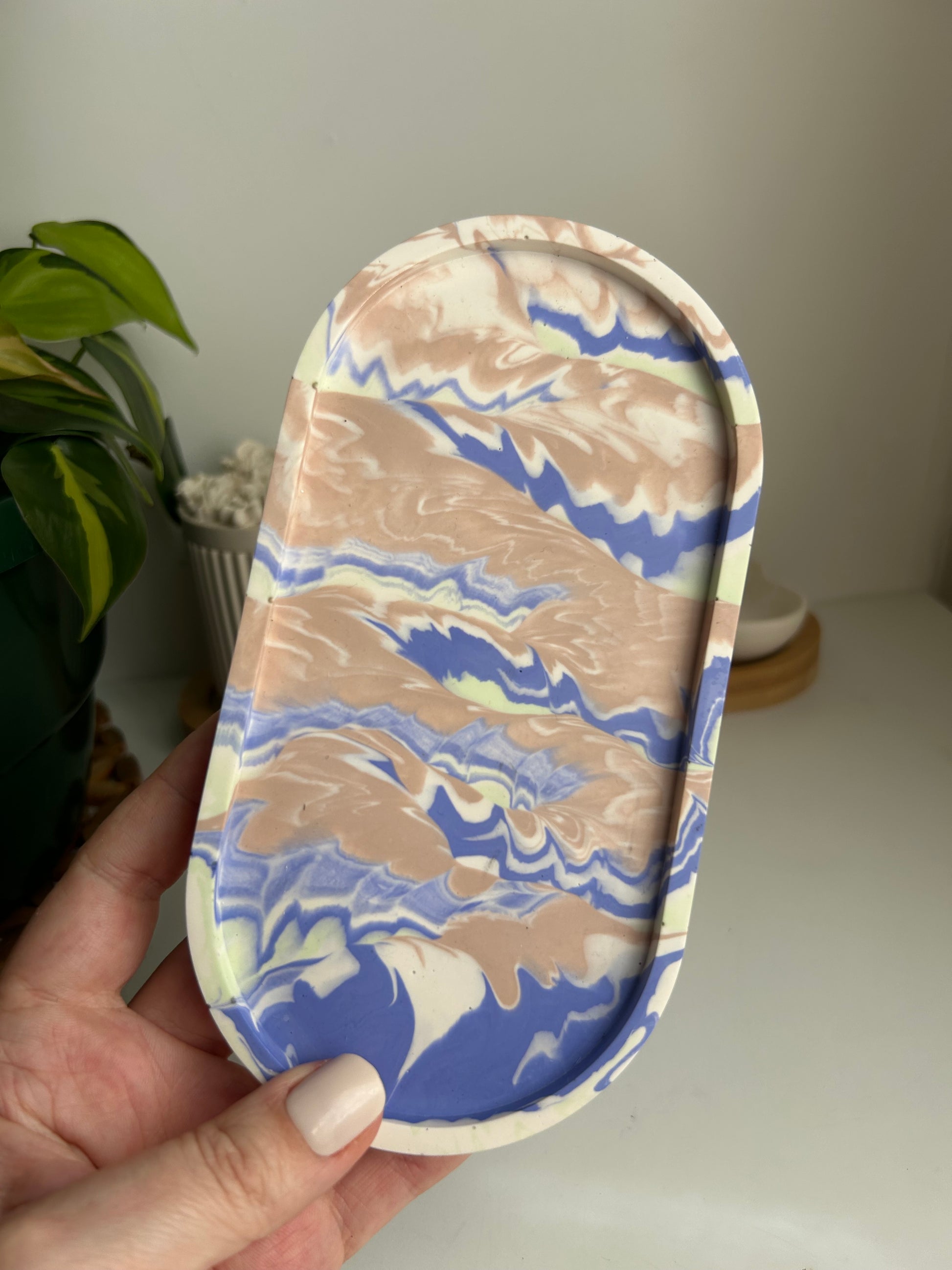 Marbled patterned tray held by a hand against a neutral background