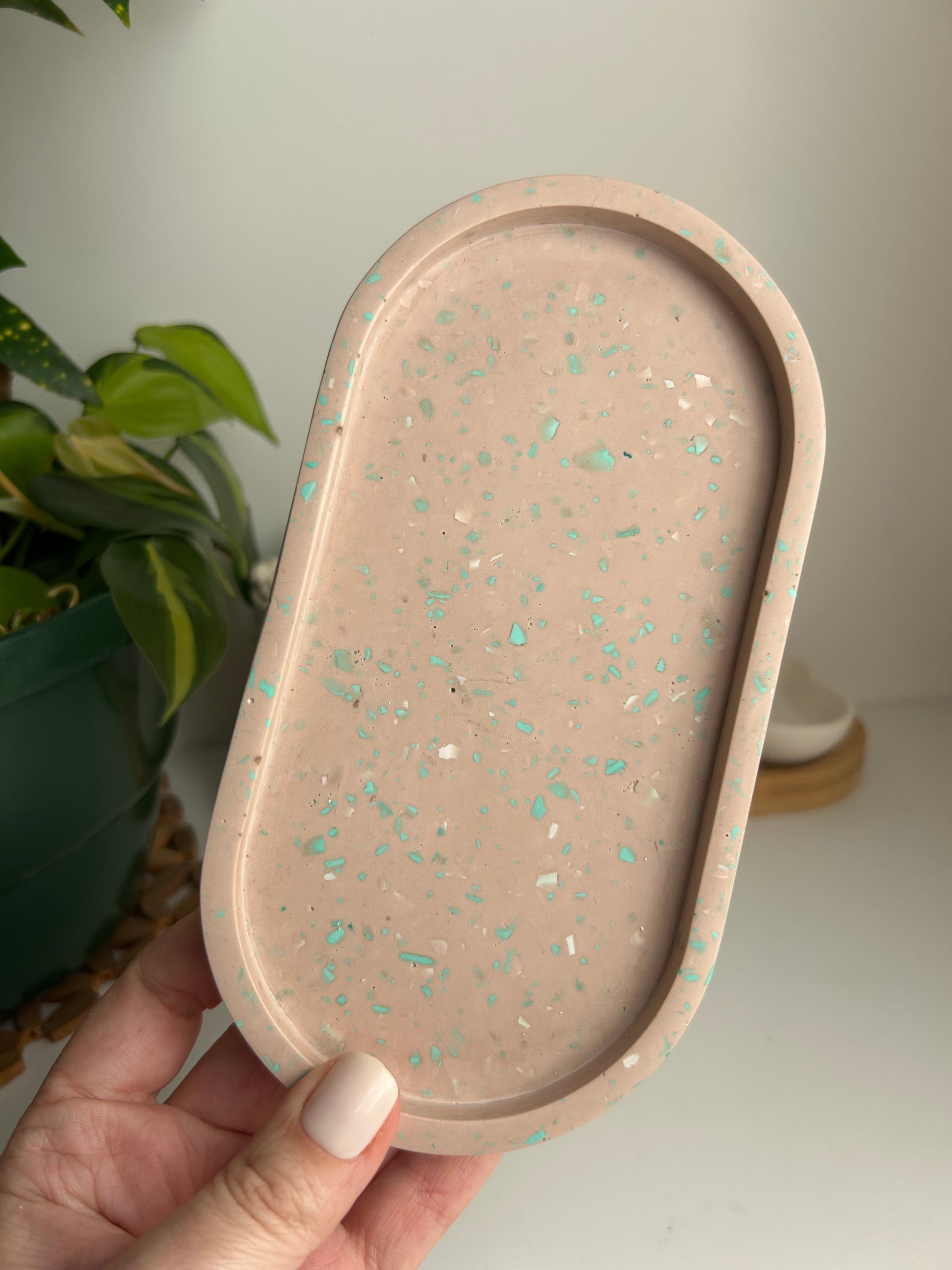 Hand holding a decorative tray with a speckled pattern against a neutral background